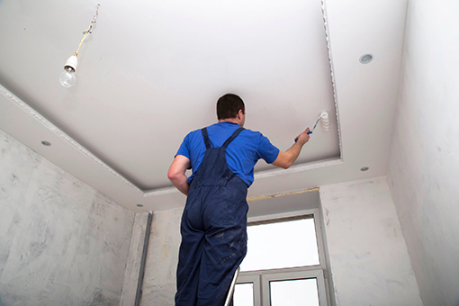 Professional Painter Using a Roller Brush to Paint Ceiling of Sun City Center House