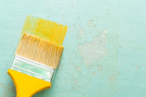 Unknown House Painter Using a Brush to Change Blue Apartment to Yellow