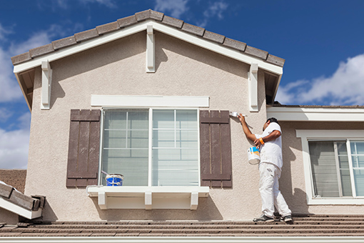 House Painter Standing on the Roof To Paint Wall of a House in Beach Park Florida