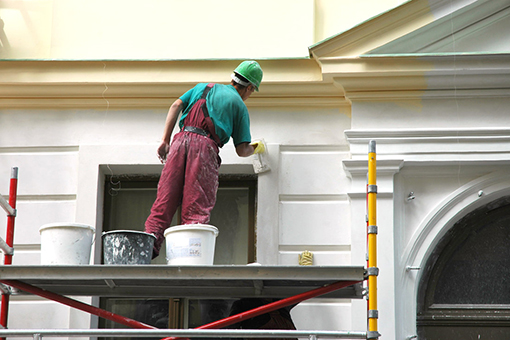 Professional House Painter Standing on a Platform During Work at West Tampa Building